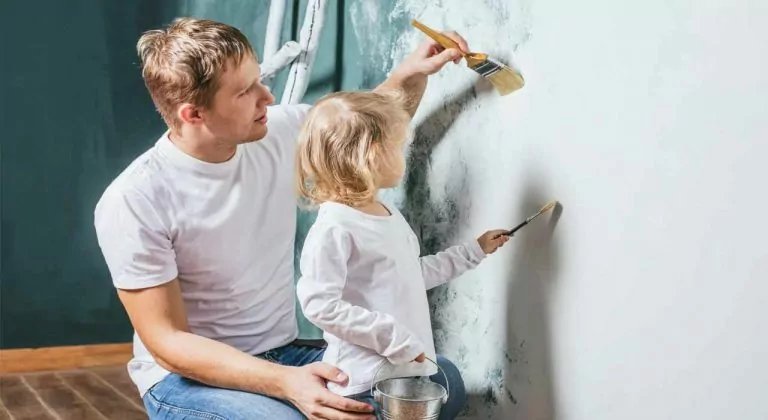 a dad and daughter painting a wall