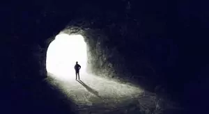 man in dark cave looking into the light